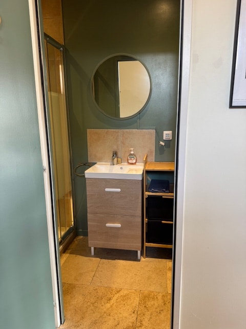 Salle de bain moderne du gite avec miroir rond et douche
